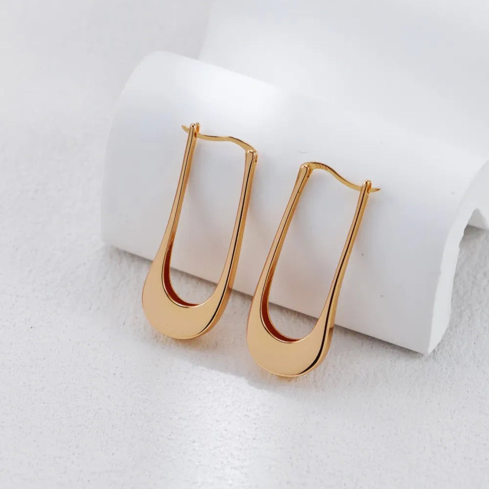Gold Silver Minimalist U-Shaped Drop Earrings in gold tone on a white curved stand