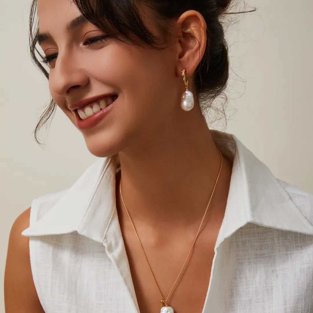 Model wearing gold-tone S925 Silver Baroque Pearl Drop Earrings and matching necklace with a white linen top