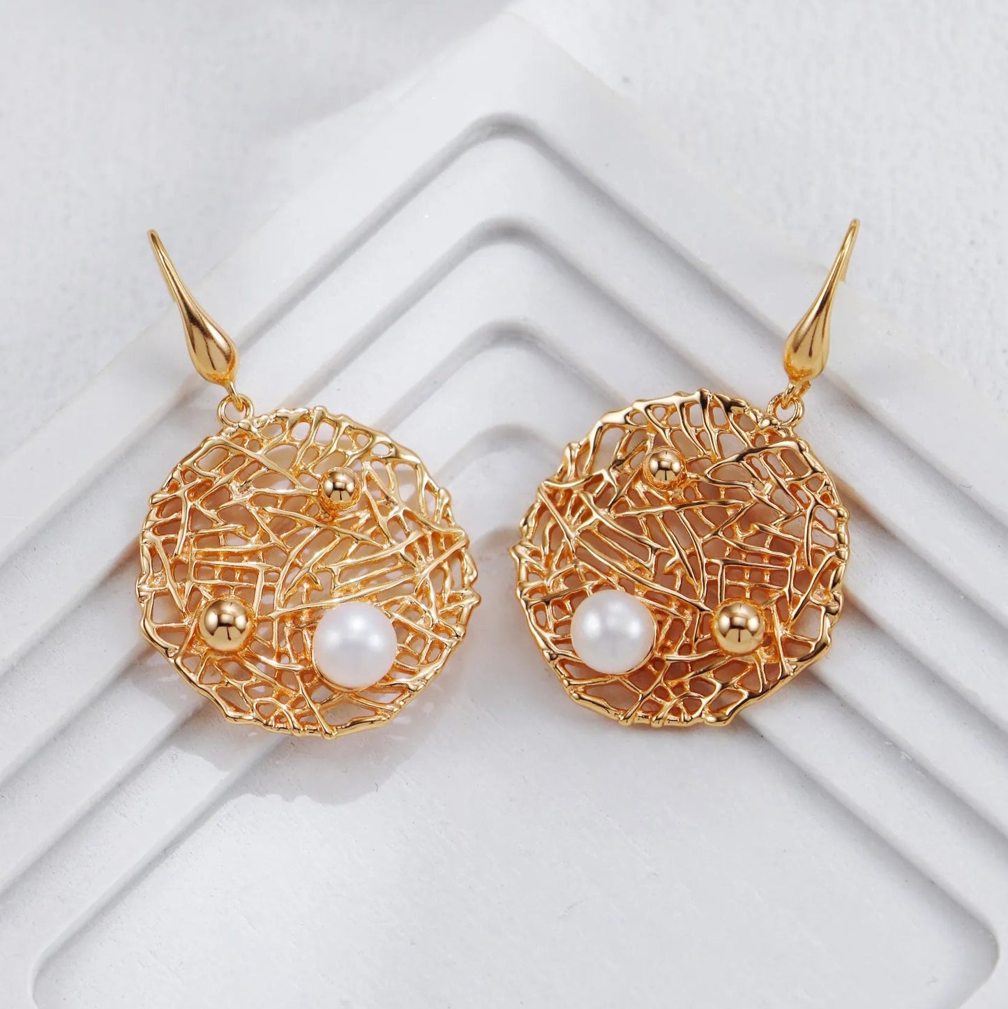 S925 Silver Metal Openwork Personalized Pearl Earrings in silver on white geometric background