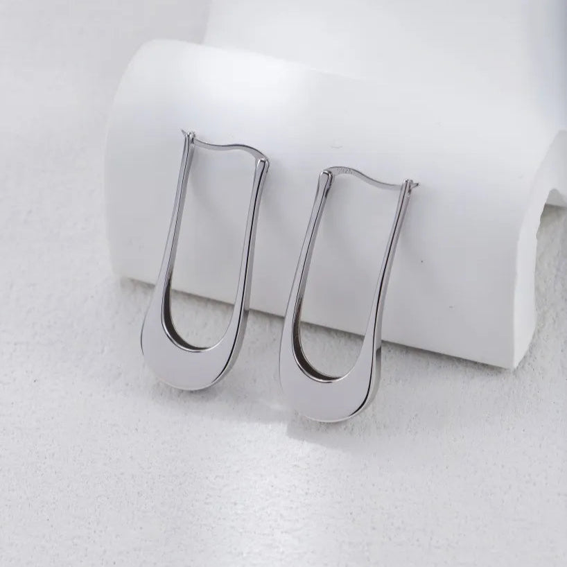 S925 Silver Minimalist U-Shaped Drop Earrings in gold tone on a white curved stand