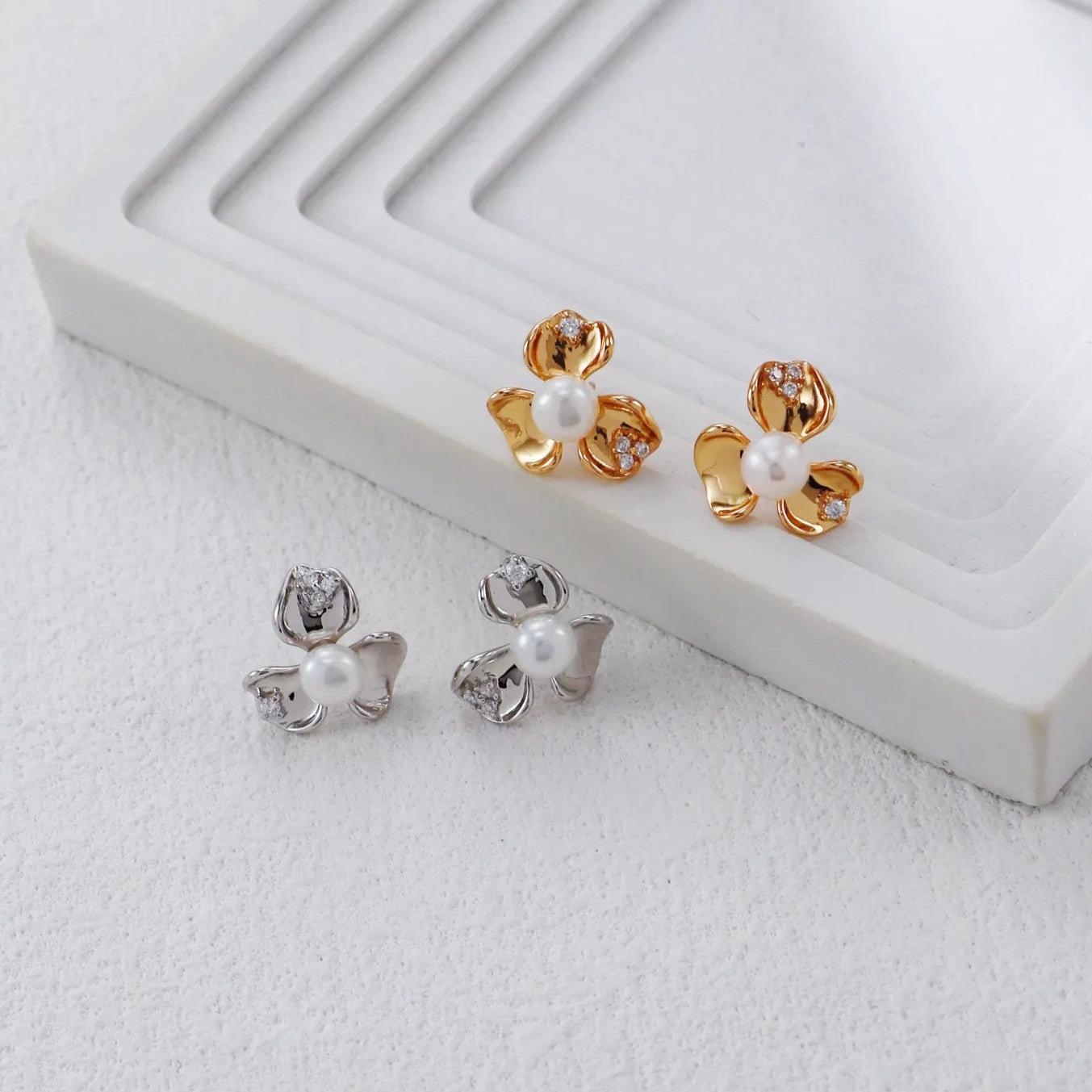 S925 Silver Petal Zircon Earrings in silver and gold tones with matching necklace and ring on white curved stand
