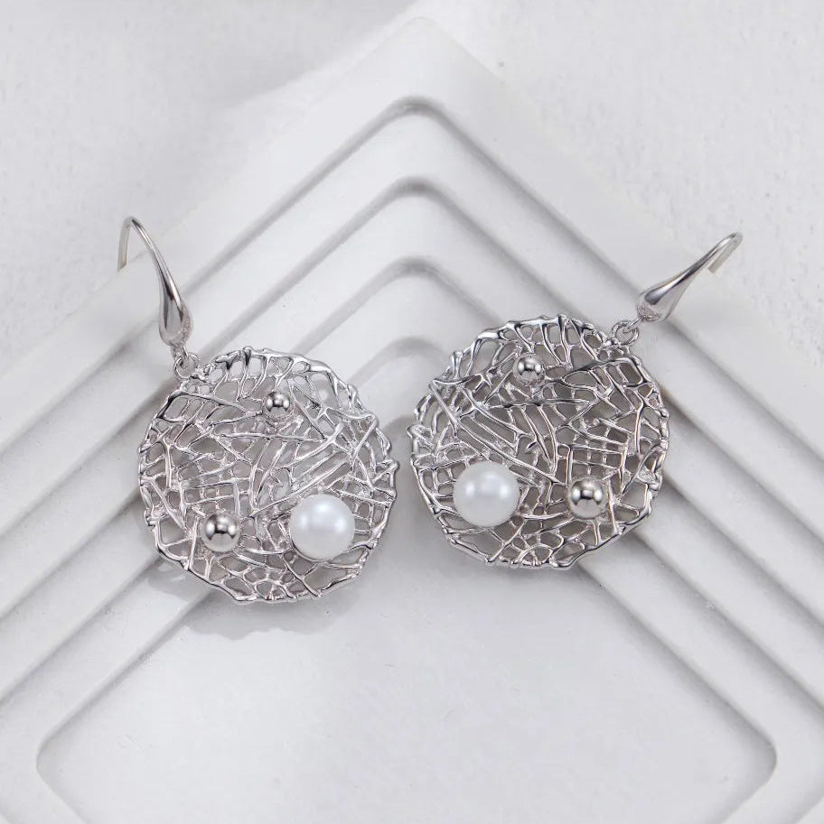 Silver Metal Openwork Personalized Pearl Earrings in silver on white geometric background